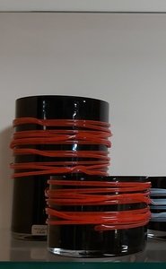Windlicht van zwart glas omringt met rode glasstringers 